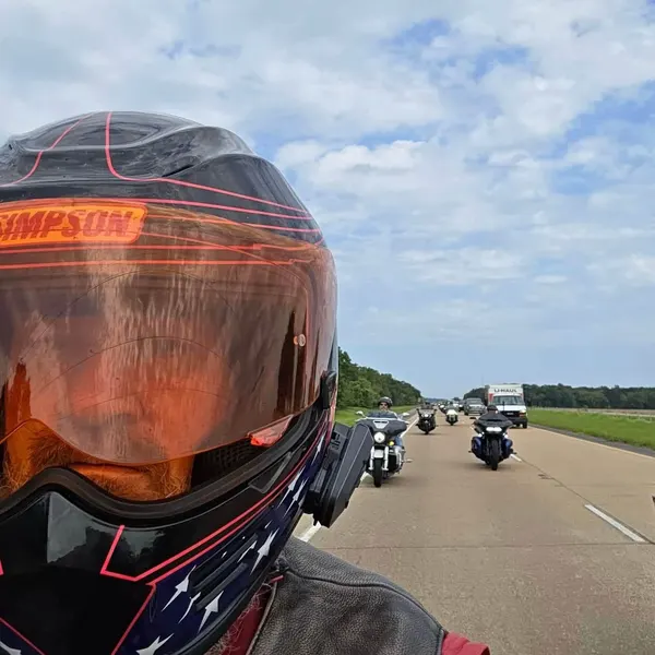 View from behind a helmeted rider with the escort strung out along the road ahead.